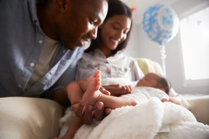 Happy young parents cuddling their newborn baby in a hospital room