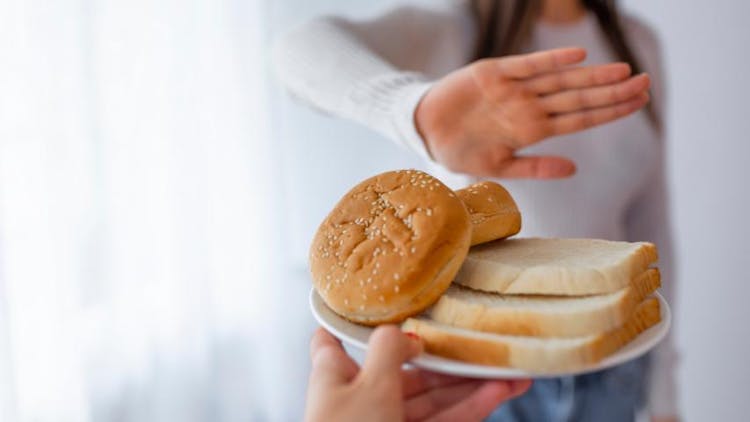 A woman on gluten-free diet refusing ot eat bread
