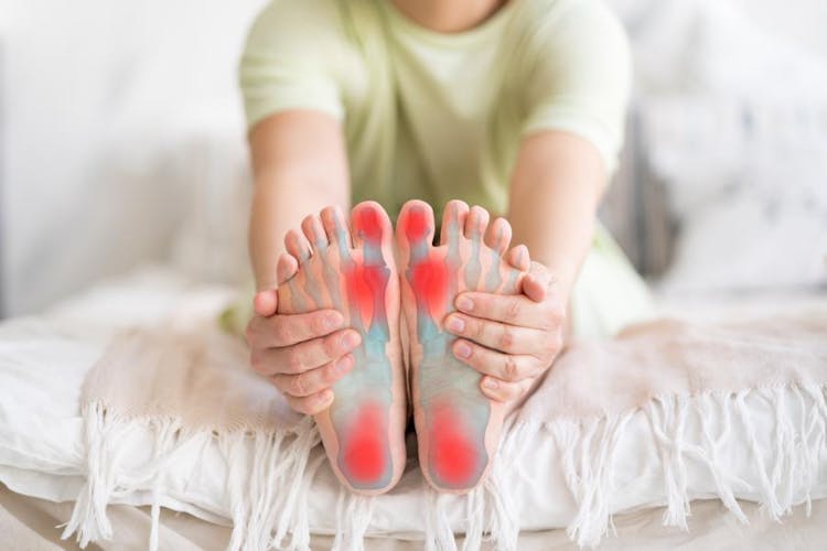 An unknown person touches the soles of their feet with red dots on the big toes and heels