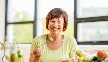 A middle age woman eating healthy food recommended for DASH diet to lower her blood pressure