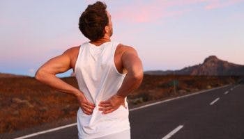 A young man suffering from lower back pain while jogging