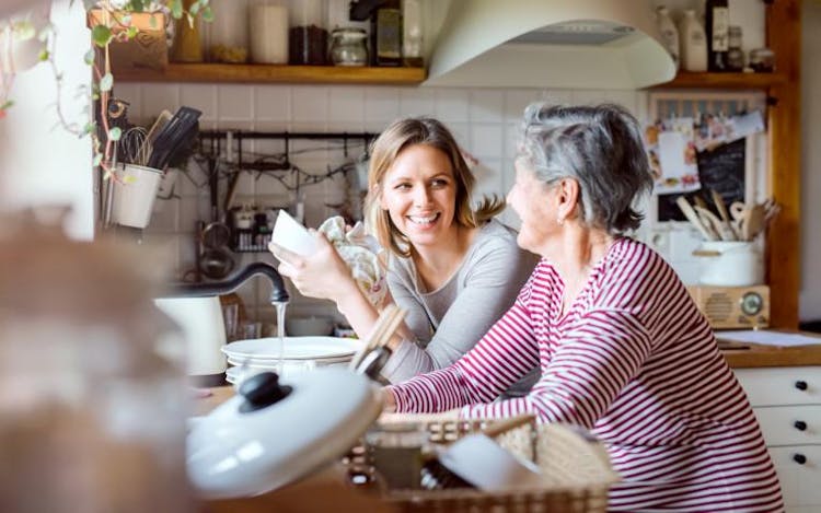 A young woman and an elderly woman talking to each other in the kitchen