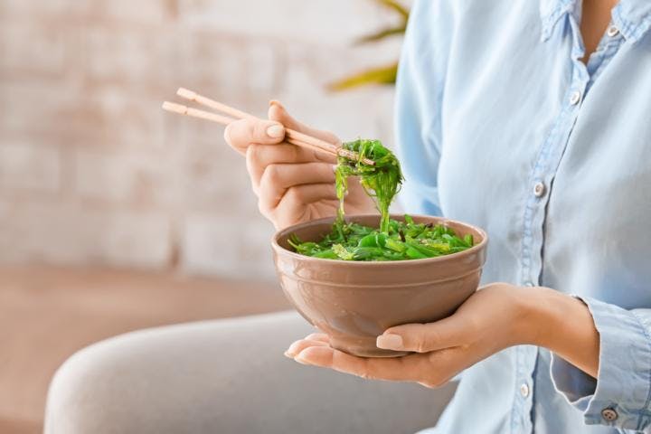 A woman eating a bowl of seaweed salad for promoting weight loss