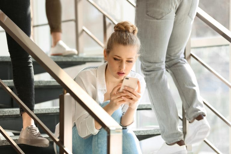 A woman sitting on a staircase while looking at her phone