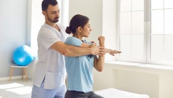 A man chiropractor or physician helps woman stretch her muscles to relieve muscle tension