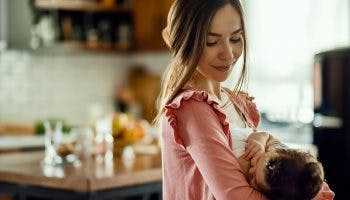 A young mother nursing and breastfeeding her baby in the kitchen