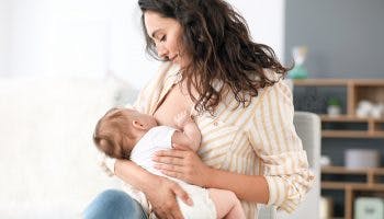 A young mother breastfeeding her baby in the living room