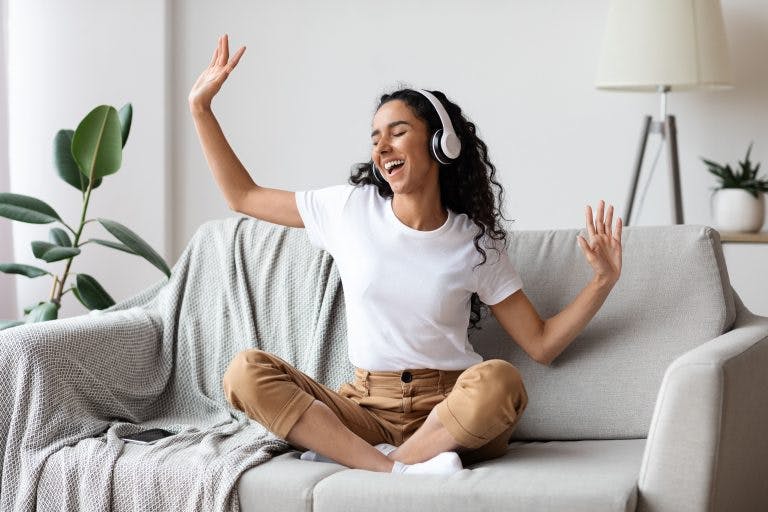 A young woman listening and dancing to music happily at home because she is free from premenstrual syndrome