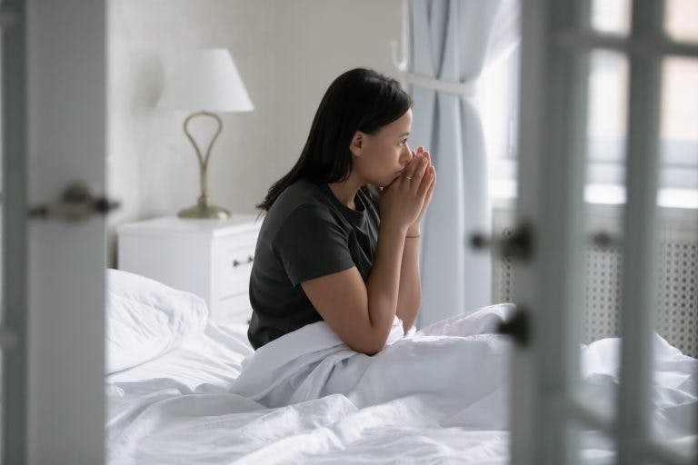 A young woman feeling somber as she is having sleep disorders due to long COVID symptoms